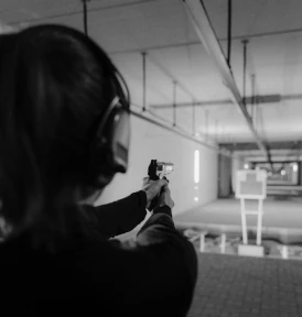 A woman aiming her firearm down a firing range.